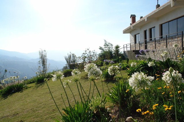 zahrada v popředí s bílými květy, s domem a krásným výhledem.jpg